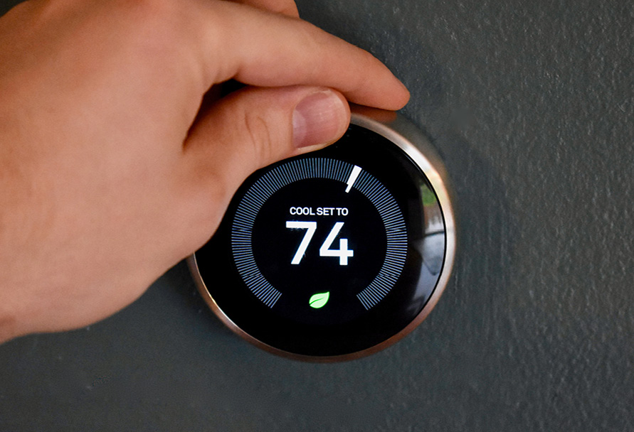 Close up of a hand on a smart thermostat