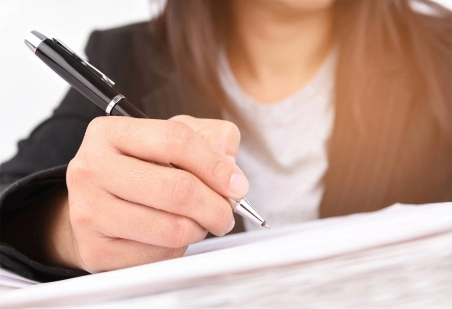 Close up of person holding a pen and filling out a form