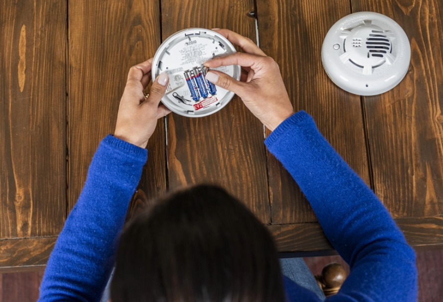 Close up of a human replacing batteries in a smoke detector
