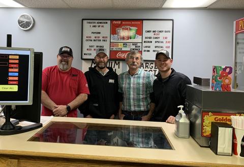 four employee volunteers standing behind movie theater concession counter