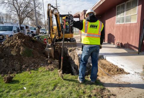 Tech digging trench next to building